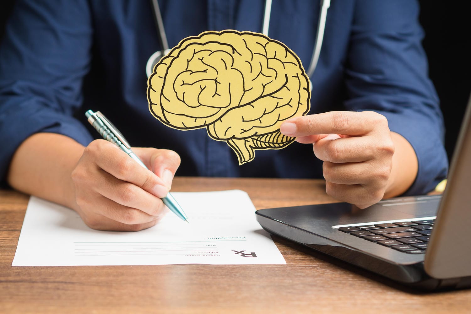 Doctor holding a brain illustration and writing a medical assessment used as expert evidence in an Ontario brain injury claim