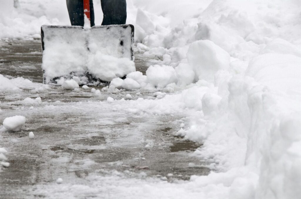 Snow being shovelled from a sidewalk in Ontario representing the winter maintenance and contractor questions central to snow and ice slip and fall claims