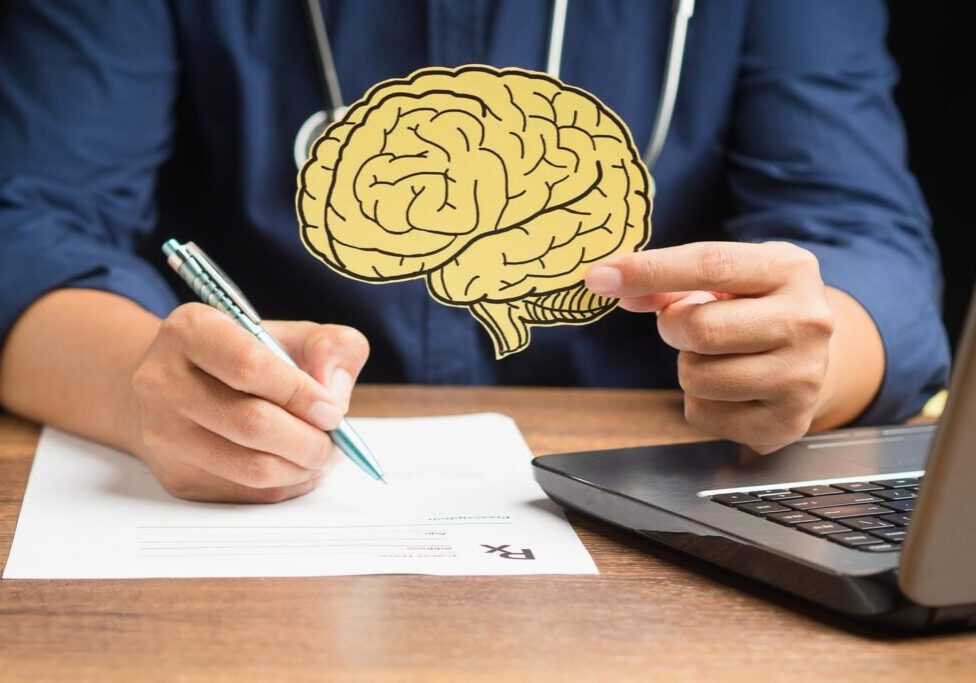Doctor holding a brain illustration and writing a medical assessment used as expert evidence in an Ontario brain injury claim
